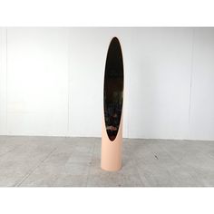 an oval shaped sculpture in the middle of a room with white walls and concrete flooring