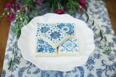 blue and white decorated cookies on a plate with purple flowers in the backgroud