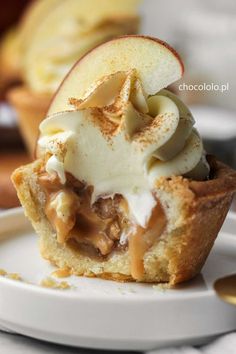 an apple pie is sitting on a plate with some ice cream in the middle and apples behind it