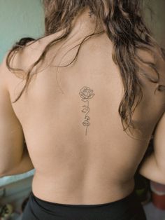 the back of a woman's body with a rose tattoo on her lower back