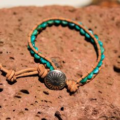 Created by the artists at Alta Studios this Turquoise Bead and Leather Wrap bracelet is hand crafted high in the mountains of Northern New Mexico. Made from genuine high quality turquoise rondelle beads, tan Greek leather cord and cast metal "Concho" button. A beautiful piece of the Southwest! This item is one of a kind - you will receive the exact item pictured. Adjustable length : Approx. 7 3/8" to 8" dia. 12 oz. Shipping Weight Handmade Turquoise Leather Bracelet Spiritual, Artisan Turquoise Beaded Bracelets Adjustable, Adjustable Turquoise Beaded Artisan Bracelets, Rustic Adjustable Turquoise Beaded Bracelets, Bohemian Turquoise Jewelry On Waxed Cord, Bohemian Turquoise Jewelry With Waxed Cord, Bohemian Jewelry In Turquoise Waxed Cord, Bohemian Jewelry In Turquoise With Waxed Cord, Adjustable Turquoise Leather Bracelet Southwestern Style