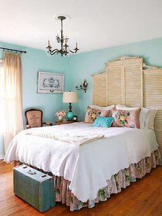 a bed sitting in a bedroom next to a window and a lamp on top of a wooden floor