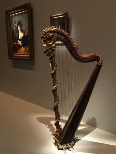 a large wooden harp sitting on top of a white floor next to two framed pictures