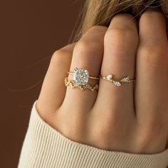 a woman's hand wearing a gold ring with a diamond on the middle and side