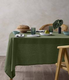 a green table cloth on top of a wooden chair next to a bowl of fruit