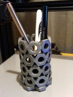 a pen holder made out of toilet paper and some pens on a table with a mirror in the background