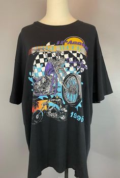 Vintage 1990s double sided Bike Week Daytona single stitch t-shirt. Black poly/cotton t-shirt with a super 90s motorcycle design backed in the classic 90s black and white checkerboard.  Back is printed in a white graphic that says " 55th Annual Bike Week Daytona Beach, Florida 96" with an eagle on top.  Good condition. Overall fade typical for age. One or two tiny pinholes. Normal amount of honest wear. Label : Tennessee River Gold Size : XL Laid flat and measured.  Shoulder to shoulder - 23 inches Chest (armpit to armpit) - 25 inches Waist - 24 inches Length - 30 inches Black Casual T-shirt With Vintage Print, Casual Black T-shirt With Vintage Print, Casual T-shirt With Front Print For Biker Events, Black Graphic T-shirt For Biker Events, Black Graphic Print T-shirt For Biker Events, Vintage Black Tops For Biker Events, Moto Style Graphic Print Crew Neck T-shirt, Moto Style Cotton Top With Graphic Print, 90s Vintage Print Black T-shirt