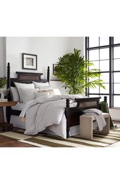 a bed with white linens and pillows in a room next to a large window