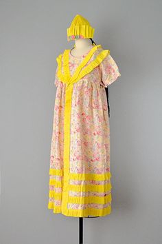 "This rare 1920's costume party dress is an unusual find for us. Made of cotton seersucker in a whimsical floral pattern, and adorned with streamers of bright yellow crepe paper. A panel of striped pink seersucker makes up the middle of the dress's front. Features puff sleeves with gathering at banded cuffs, an empire waist with matching ties at sides for a slight adjustment to fit, and crew neckline. The yellow crepe paper cascades down the front of the dress, decorates the neckline and yoke, a 1950s Vintage Summer Dress With Ruffles, 1950s Vintage Ruffled Dress For Summer, 1950s Style Vintage Ruffled Dress For Summer, 1950s Ruffled Vintage Dress For Spring, 1920s Style Spring Daywear Dresses, 1920s Style Spring Day Dresses, 1920s Style Day Dresses For Spring, Paper Costume, 20s Dress