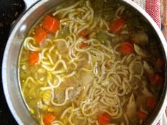 a pot full of soup with noodles and carrots