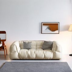 a living room with white walls and furniture in the corner, including a couch that has black and white pillows on it