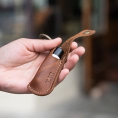 a hand holding a leather case with a lighter in it's left side pocket