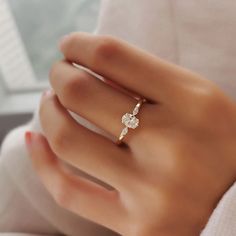 a woman's hand wearing a gold ring with two diamonds on the middle and one diamond in the middle