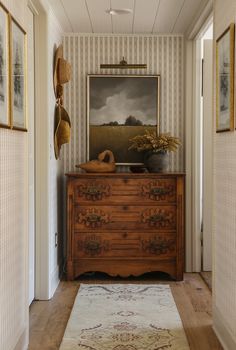 a room with a dresser and pictures on the wall