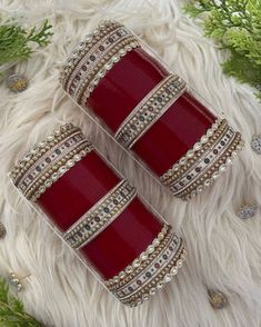 two red and gold bangles sitting on top of a white fur covered floor