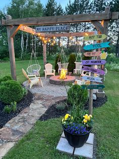 a wooden sign sitting on top of a lush green field next to a flower garden