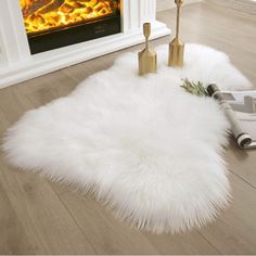 a white sheepskin rug on the floor in front of a fire place with candles