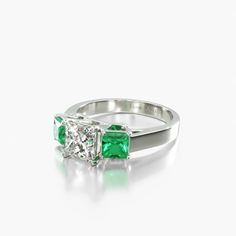 an emerald and diamond engagement ring set in yellow gold with two diamonds on each side