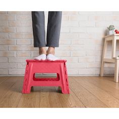 a person standing on a step stool in front of a brick wall and wooden floor