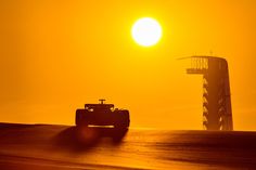 the sun is setting behind a racing car