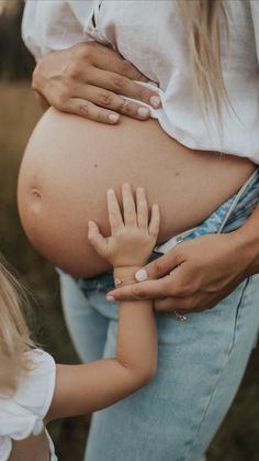 a pregnant woman holding her child's hand while she holds the baby's belly