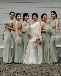 a group of women standing next to each other wearing dresses and holding bouquets in their hands