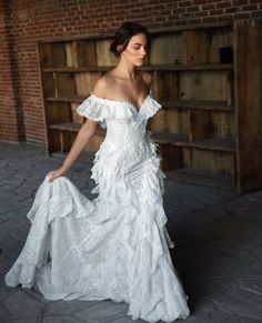 a woman in a white dress is standing near a book shelf and she has her hand on the back of her shoulder