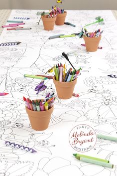 several clay pots filled with crayons sitting on top of a white paper covered table