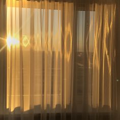 the sun shines brightly through sheer curtains