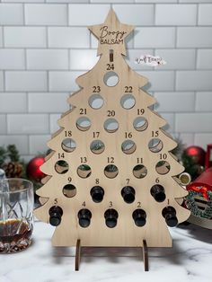 a wooden christmas tree with holes in the middle on a table next to some glasses