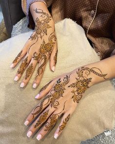 two hands with henna tattoos on them