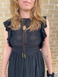 a woman in a black dress with a yellow necklace on her neck and hands behind her back