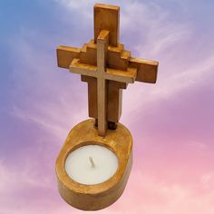 a wooden cross hanging from the side of a toilet with a lit candle in it