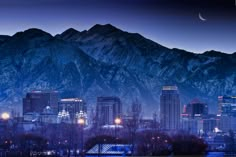 the city lights are on in front of mountains