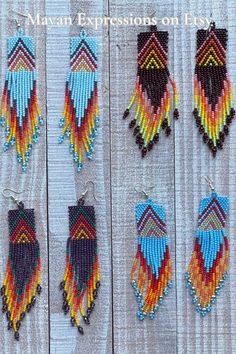 several colorful beaded earrings hanging from wooden boards