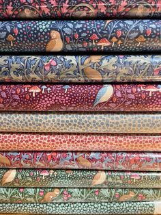 a stack of colorful fabrics with birds and flowers on them, all in different colors