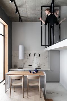 two people are standing on the stairs above a table and chairs in a modern kitchen