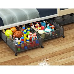 two bins filled with toys on top of a wooden floor next to a bed