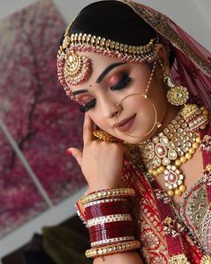 a woman in a red and gold bridal outfit with her hands on her face