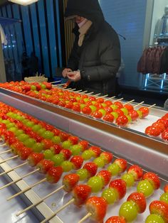 a person in a black hoodie is making some food on a rack with skewers