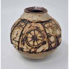 a brown and white vase sitting on top of a table