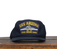 the uss arizona hat is sitting on top of a wooden table