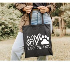 a person holding a black bag with peace love dogs on it