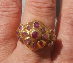 This true antique ring is luscious on all sides. The top of the ring is early 18th century and it is dotted with genuine rubies with a central floral pattern and tri shaped sides. This particular style of ring is typical of the 18th century Iberian area, most likely Portugal. The top was affixed on to a 14k gold ring  (marked 14k),shank that is elaborately hand chased and custom made by a very competent gold smith to mirror the side profiles of the ring head. The shank is marked 14k and is presently a size 6 1/2. The shank is substantial in its weight and thickness. The style of the ring suggests this work was done in 1920's. The central ruby has been replaced as well as one of the petal rubies, but this is nicely done.  A very nice ring that is very comfortable to wear. Follow me on insta Antique Ruby Ring With Rose Cut Diamonds, Traditional Hallmarked Ruby Ring, Traditional Yellow Gold Ruby Ring, Victorian Yellow Gold Ruby Ring With Intricate Design, Victorian Ruby Ring In Yellow Gold With Intricate Design, Traditional Ruby Rings For Ceremonial Occasions, Traditional Ceremonial Ruby Rings, Traditional Oval Ruby Ring, Antique Hallmarked Ruby Ring