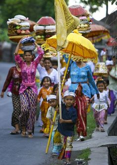 a group of people walking down a street with umbrellas on their heads and some carrying food