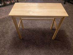 a wooden table sitting on top of a carpeted floor next to a book shelf