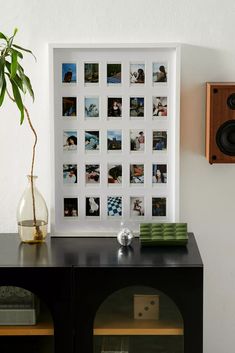 a black table topped with a vase filled with flowers and pictures next to a wall mounted speaker