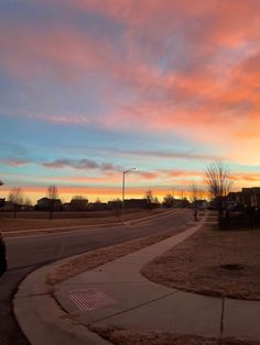 the sun is setting over an empty street