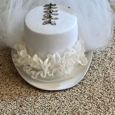 "Wedding white, felt top hat with accents of white tulle, silver leaf trims accented with silver pearls.  Hat encircled with triple layered lace with white pearls.  Front Veil covers face and neck and can fold back to enhance back veil.  Back white tulle veil is approx. 18\" long.  Silver leaf trim comes up the back of top hat and continues on the top of hat.    Fits most adult heads.  Includes white adhesive padding strips to reduce size of opening. All my designs are one-of-a-kind.  Made in a peaceful setting in Lakeside, OR USA Props not included." White High Crown Costume Hat For Church, White High Crown Hat For Church, Wedding Top Hat For Halloween, White High Crown Top Hat For Church, White Costume Hat With Round Crown For Parties, Whimsical White Costume Hats And Headpieces For Party, Whimsical White Hat Headpiece, White Mini Hats For Halloween Party, White High Crown Fascinator For Wedding