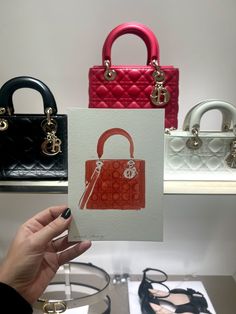 a person holding up a card with a handbag on it and other purses behind them